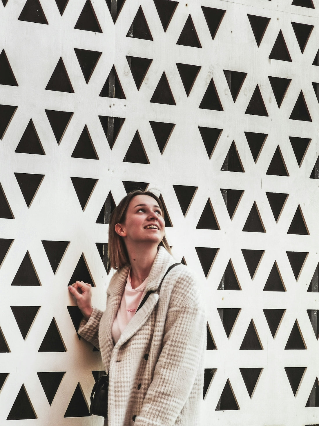 woman in white knit sweater standing beside white wall
