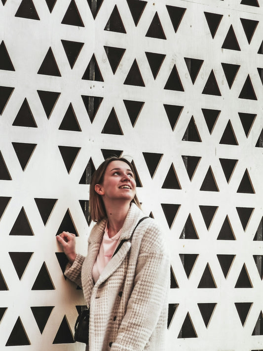 woman in white knit sweater standing beside white wall