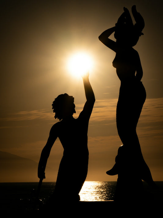 Statues silhouetted against the bright sunset