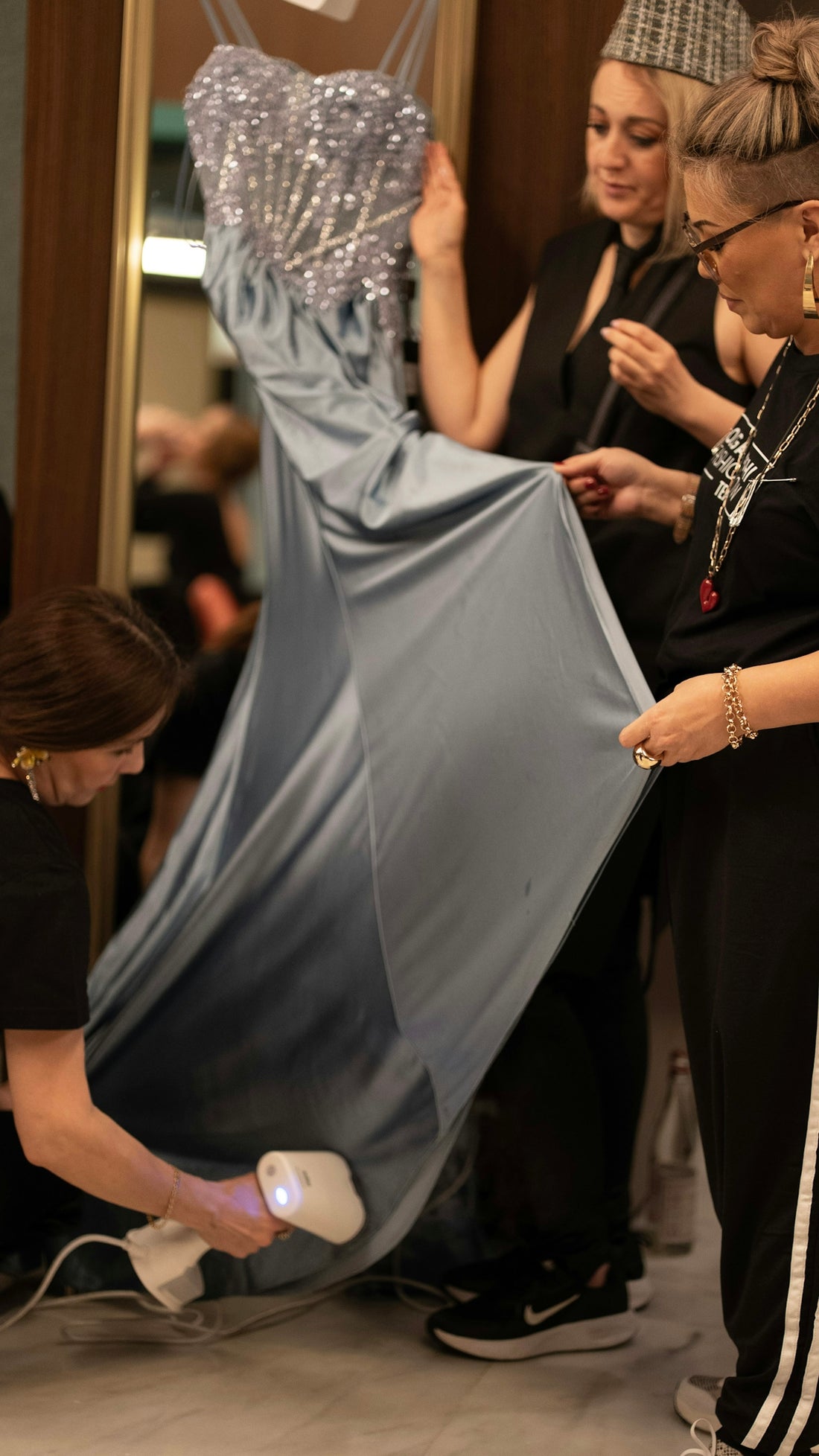 People are prepping a dress with a steamer.