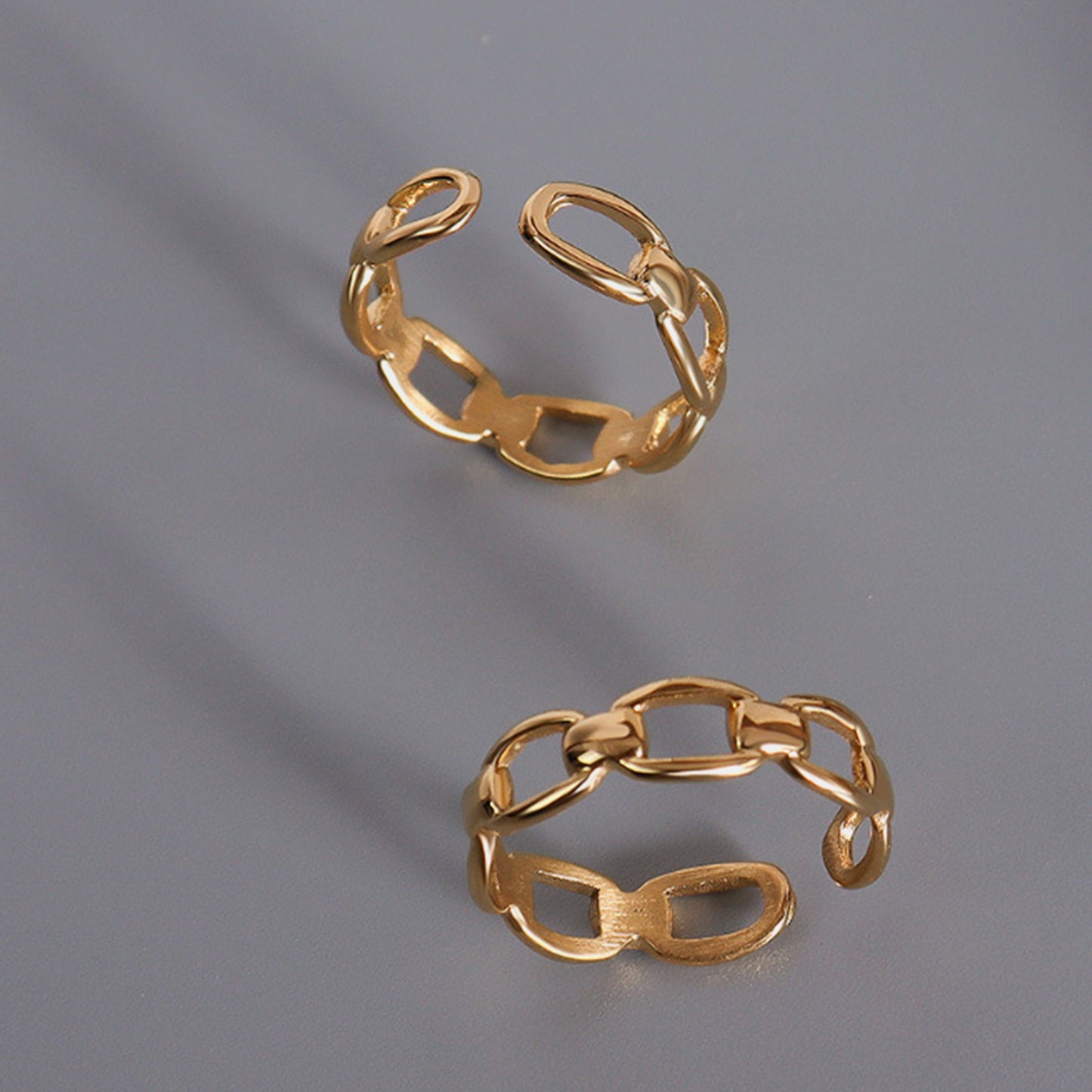 Elegant titanium steel gold-plated adjustable rings showcased on a gray background, perfect for versatile styling.
